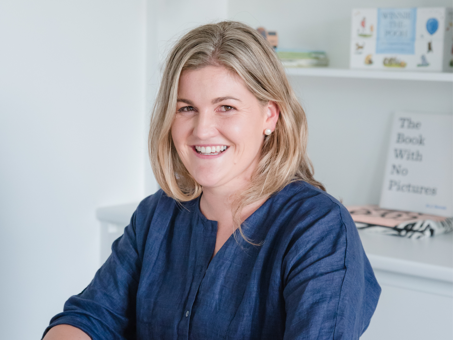 Smiling woman with blonde hair wearing a navy blue top, a podcast cover.