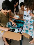 The Therapy At Home Self-Care Program features an open teal gift box filled with lotions, a striped bag, skincare essentials, cards, a hairbrush, and more—perfectly arranged for your self-care routine.