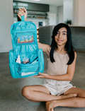 The Therapy At Home Self-Care Program features an open teal gift box filled with lotions, a striped bag, skincare essentials, cards, a hairbrush, and more—perfectly arranged for your self-care routine.