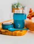 The Lunch Box Program by Therapy At Home comes in a teal and blue patterned box with stainless steel containers, a blue cup, activity cards, planners, a game, and labels—all neatly packed and partially displayed.