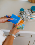 The Lunch Box Program by Therapy At Home comes in a teal and blue patterned box with stainless steel containers, a blue cup, activity cards, planners, a game, and labels—all neatly packed and partially displayed.
