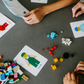 An open blue and green box from Therapy At Home's Build it with Bricks Foundation Program includes two LEGO Classic sets and colorful activity cards—ideal for supporting executive function skills in therapy sessions—displayed on a plain light background.