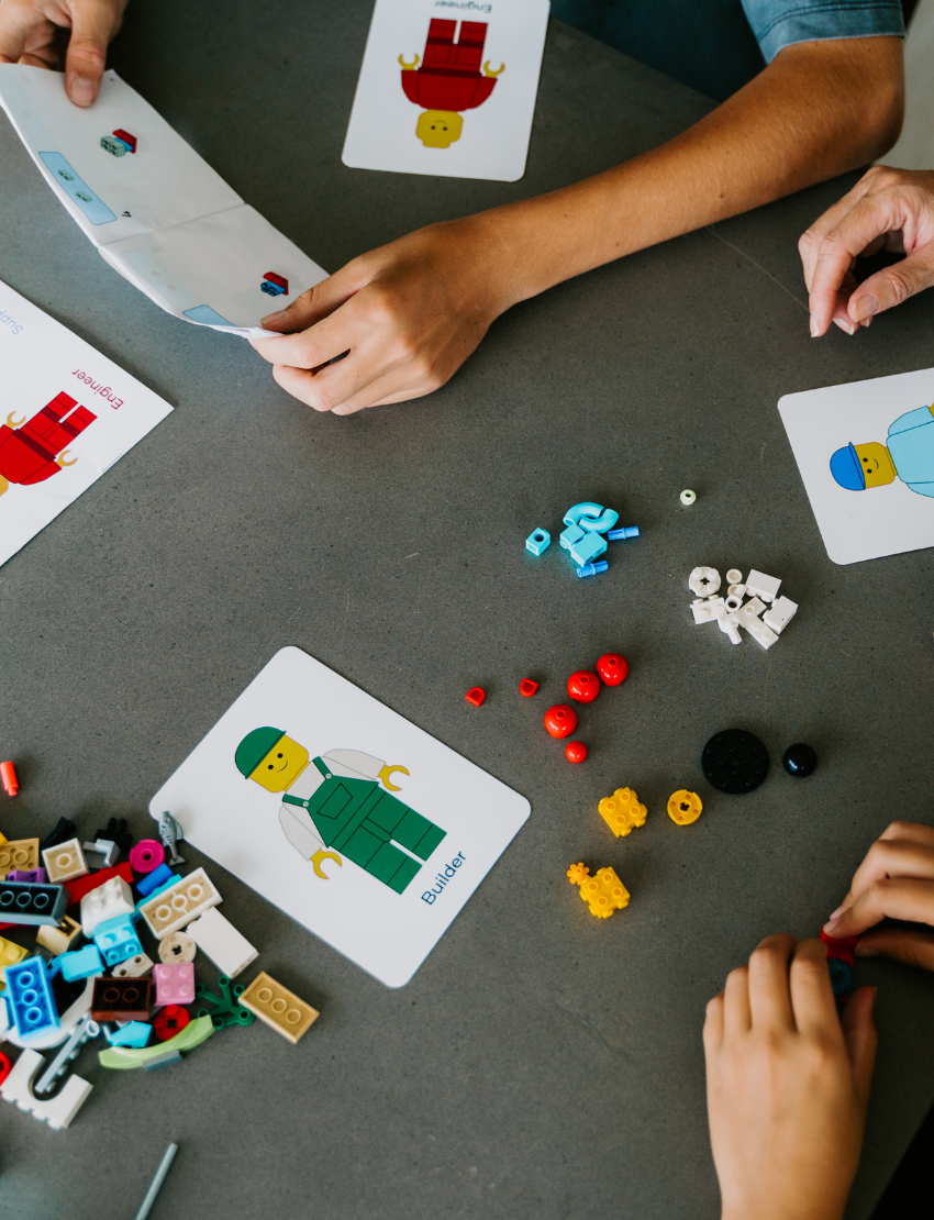 An open blue and green box from Therapy At Home's Build it with Bricks Foundation Program includes two LEGO Classic sets and colorful activity cards—ideal for supporting executive function skills in therapy sessions—displayed on a plain light background.
