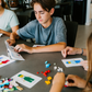 An open blue and green box from Therapy At Home's Build it with Bricks Foundation Program includes two LEGO Classic sets and colorful activity cards—ideal for supporting executive function skills in therapy sessions—displayed on a plain light background.