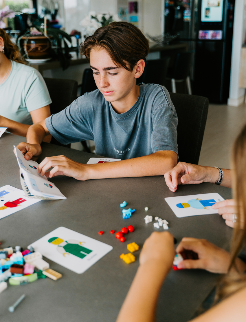 An open blue and green box from Therapy At Home's Build it with Bricks Foundation Program includes two LEGO Classic sets and colorful activity cards—ideal for supporting executive function skills in therapy sessions—displayed on a plain light background.