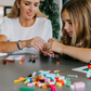 An open blue and green box from Therapy At Home's Build it with Bricks Foundation Program includes two LEGO Classic sets and colorful activity cards—ideal for supporting executive function skills in therapy sessions—displayed on a plain light background.