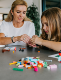 An open blue and green box from Therapy At Home's Build it with Bricks Foundation Program includes two LEGO Classic sets and colorful activity cards—ideal for supporting executive function skills in therapy sessions—displayed on a plain light background.