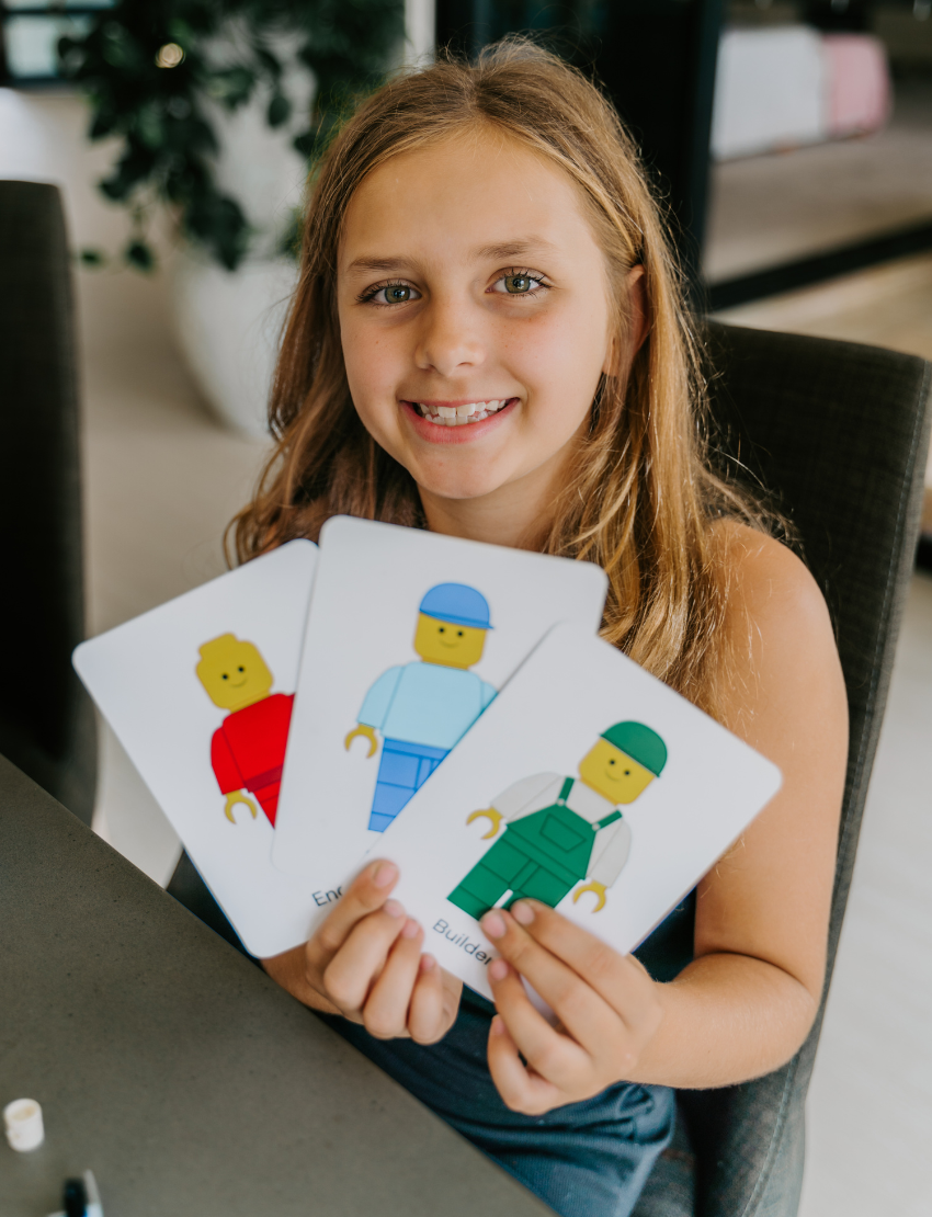An open blue and green box from Therapy At Home's Build it with Bricks Foundation Program includes two LEGO Classic sets and colorful activity cards—ideal for supporting executive function skills in therapy sessions—displayed on a plain light background.