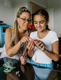 The Express Yourself Program by Therapy At Home features a teal and purple box with paint, markers, brushes, worksheets, bead kit, colored paper, a white cap, and a paint palette—perfect for occupational therapy activities.