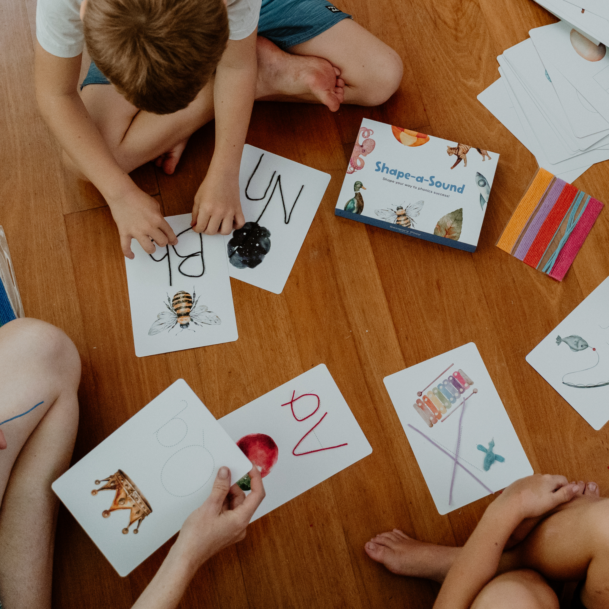 Children playing with flashcards on a wooden floor