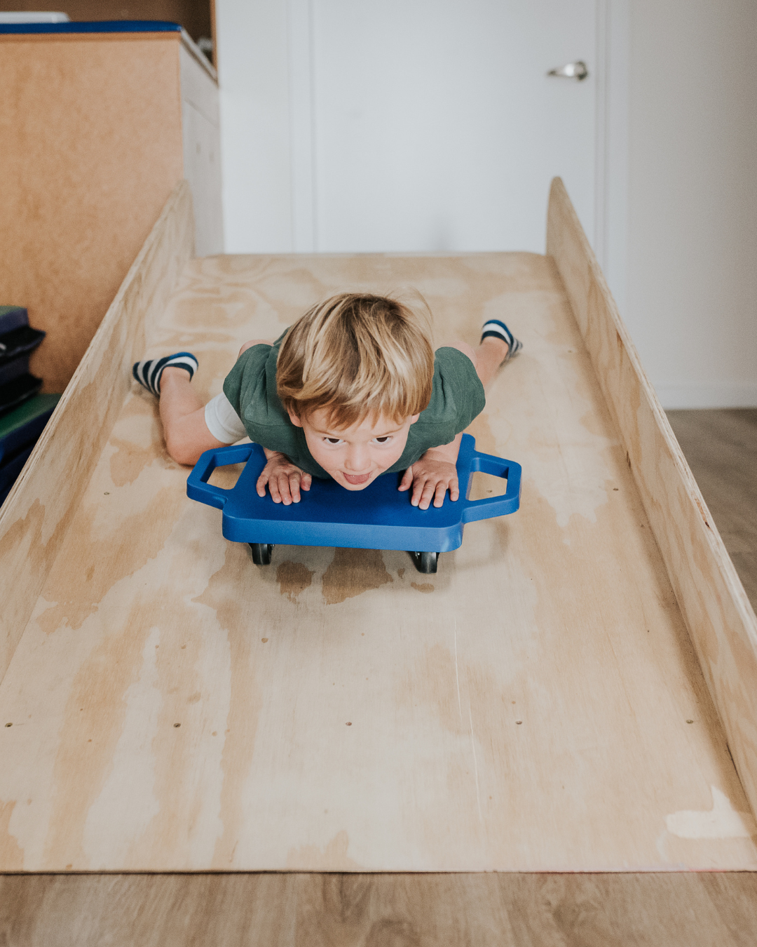 Boy on a scooter sliding down a wooden ramp
