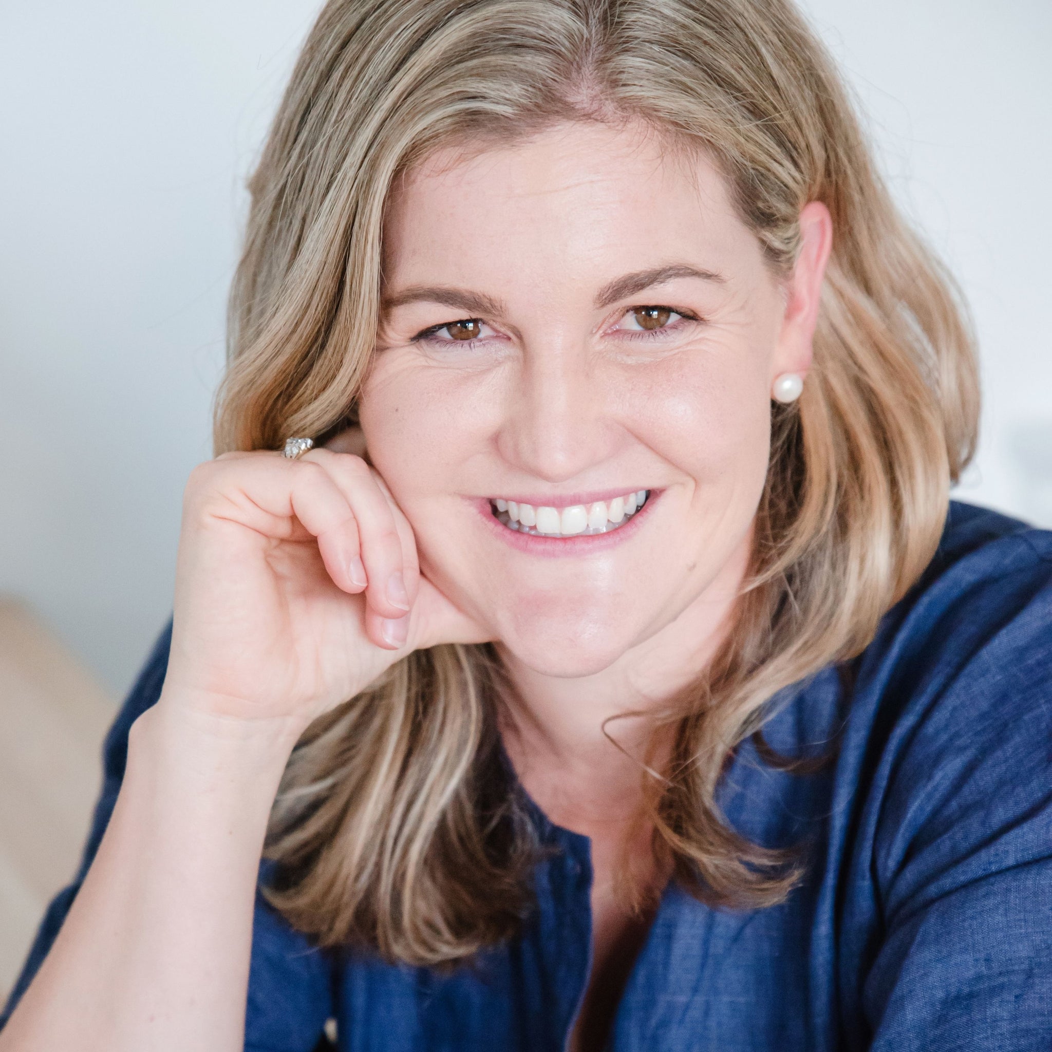 Close-up portrait of Kait Cummins, smiling with her hand on her chin.