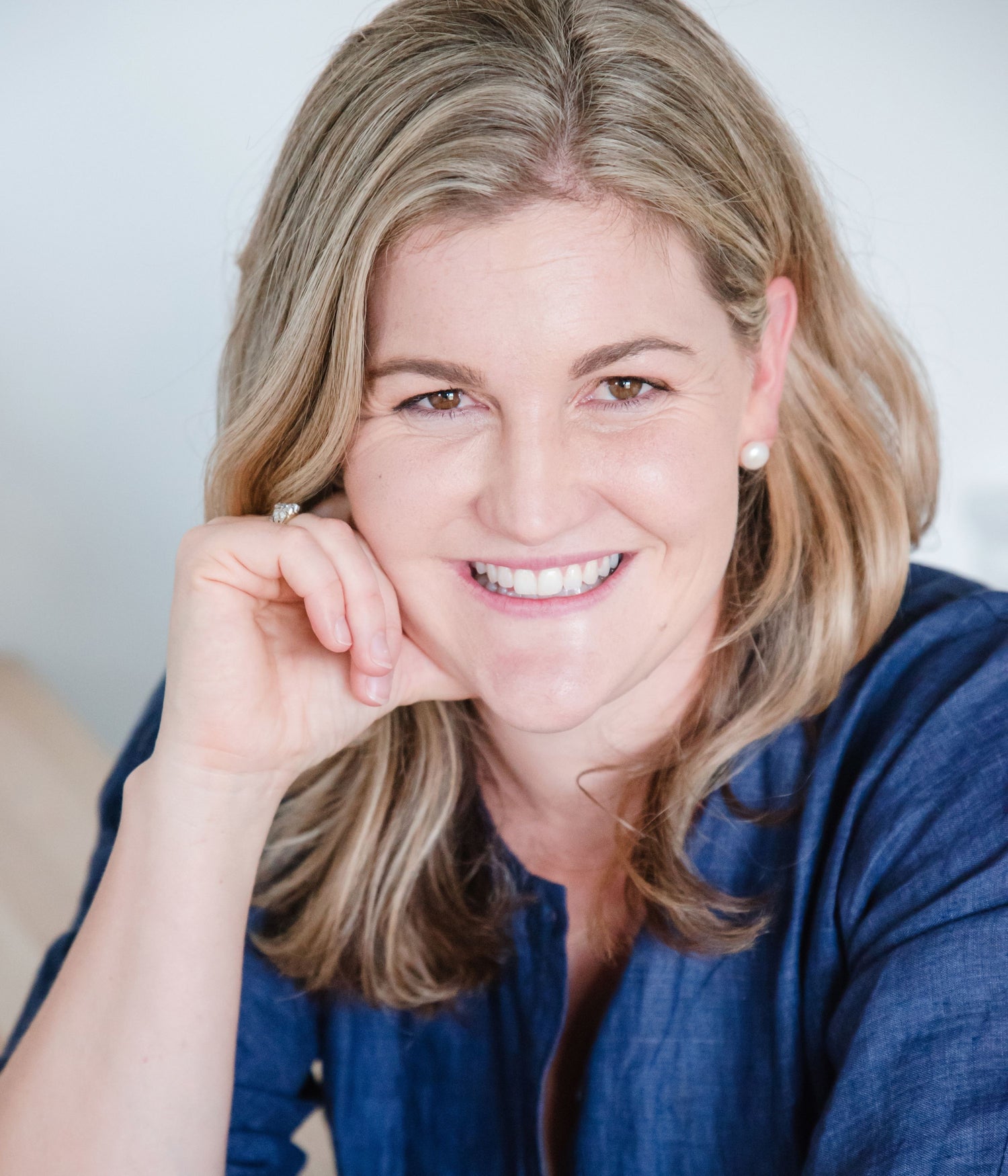 Close-up portrait of Kait Cummins, smiling with her hand on her chin.