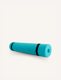 A rolled-up large turquoise yoga mat from The Play Way brand, secured with black straps. The text 