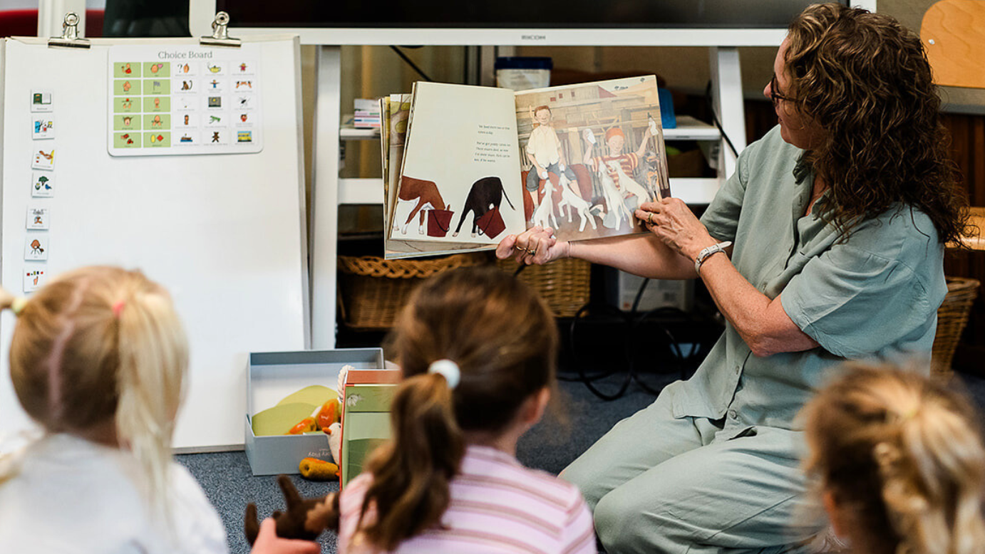 Teacher reading a book to children in a classroom setting